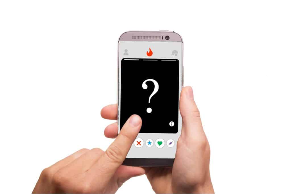 Een hand houdt een smartphone vast met een dating-app-interface. Op het scherm wordt een zwarte profielkaart weergegeven met een groot vraagteken in het midden, wat een onbekend profiel aangeeft. Knoppen voor het leuk vinden, niet leuk vinden en andere interacties zijn onderaan zichtbaar, wat doet denken aan moderne digitale matchmaker-tools.