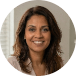 Glimlachende vrouw met halflang bruin haar, draagt een lichtgekleurd topje, zit binnen met een neutrale achtergrond, overweegt het aanbod voordat ze zich inschrijft.