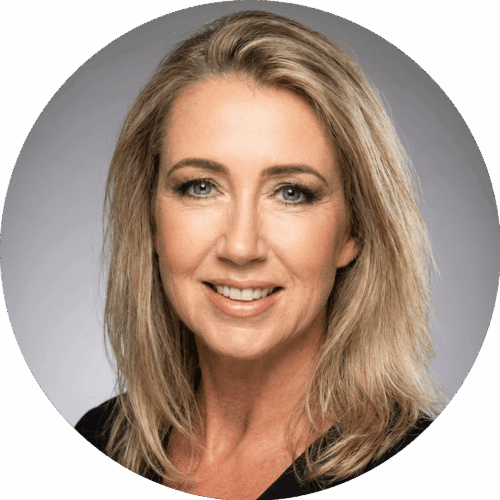 Een vrouw met schouderlang blond haar en lichte ogen glimlacht naar de camera. Ze draagt een zwart topje en heeft natuurlijke make-up. De achtergrond is een neutraal grijs verloop.